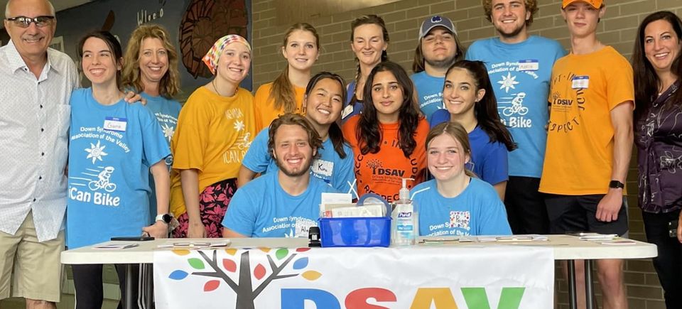 DSAV volunteers and community members gathered behind an information table at a community event.