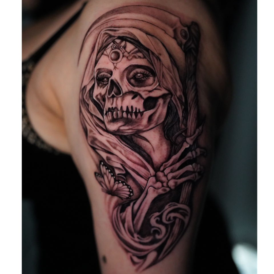 Image of a royal tattoo as a skeleton adorned with head wrapping and sceptor and a butterfly