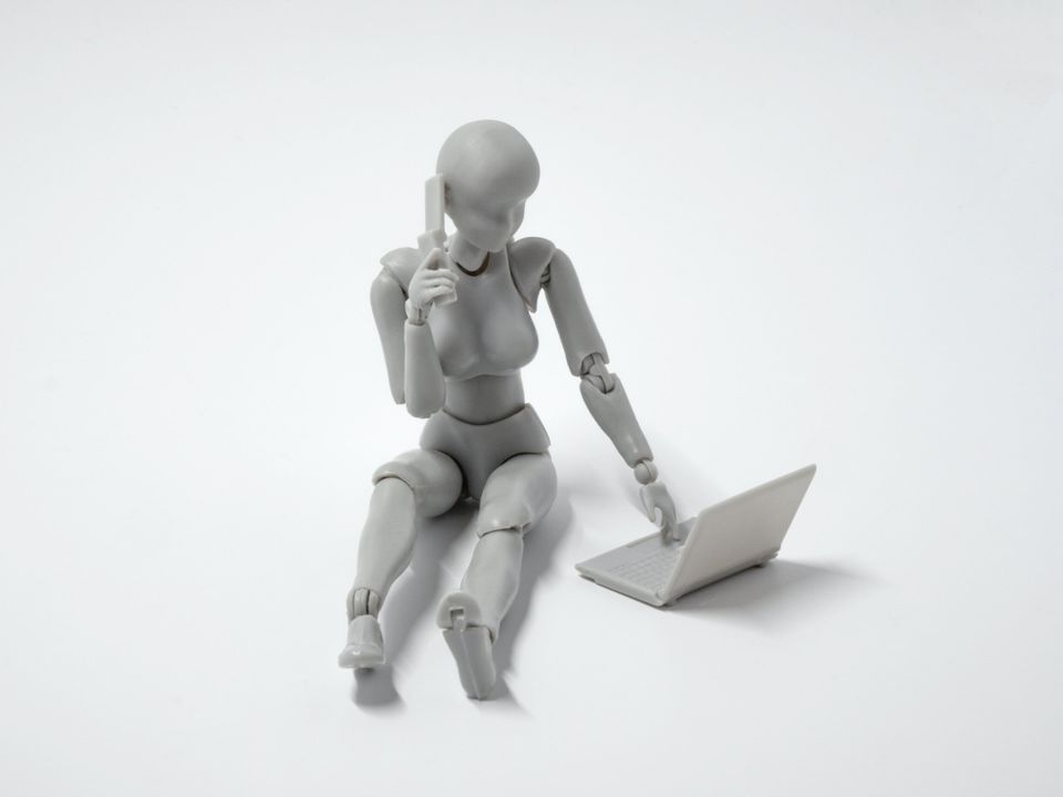 A solo AI robot (wooden toy painted white) on a laptop with a phone to its ear