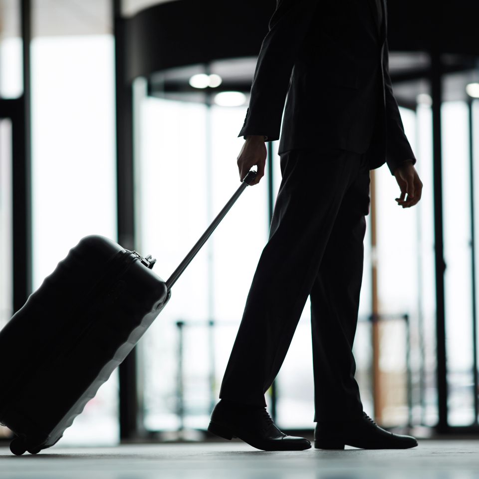 Silhouette of lowsection of business traveler with suitcase moving down modern airport