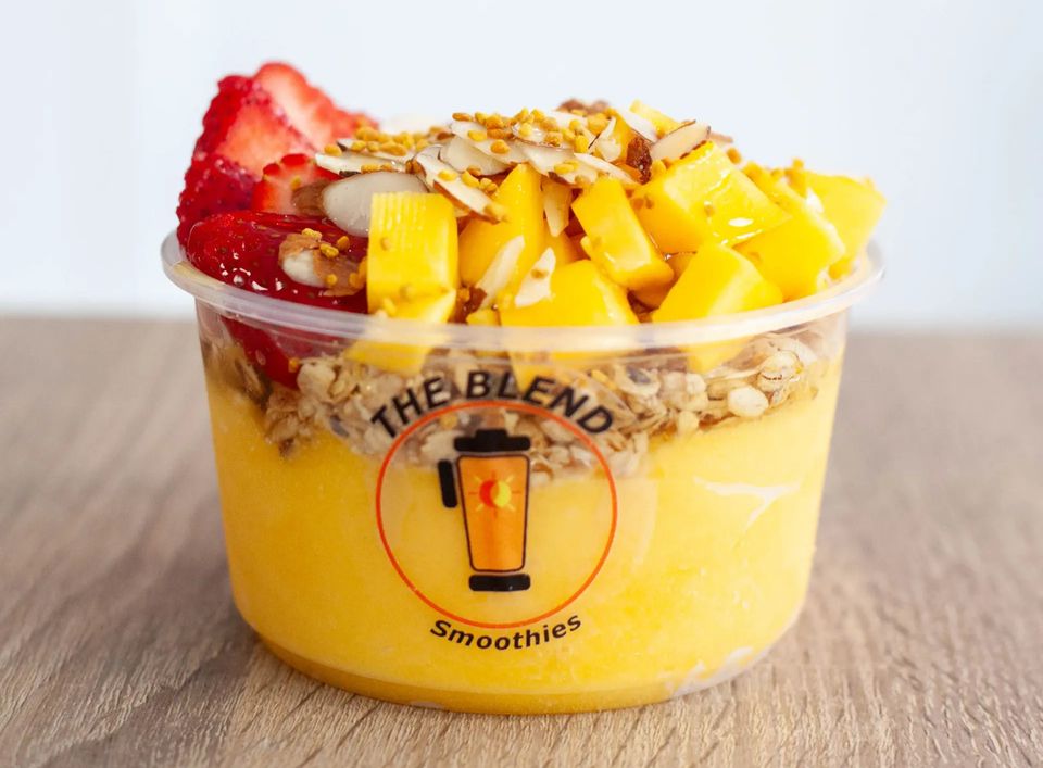 The Blend – A tropical mango-based bowl topped with mango, strawberries, bee pollen, almonds, granola, and a drizzle of agave. The Blend bowl with mango base, mango, strawberries, bee pollen, almonds, granola, and agave drizzle.