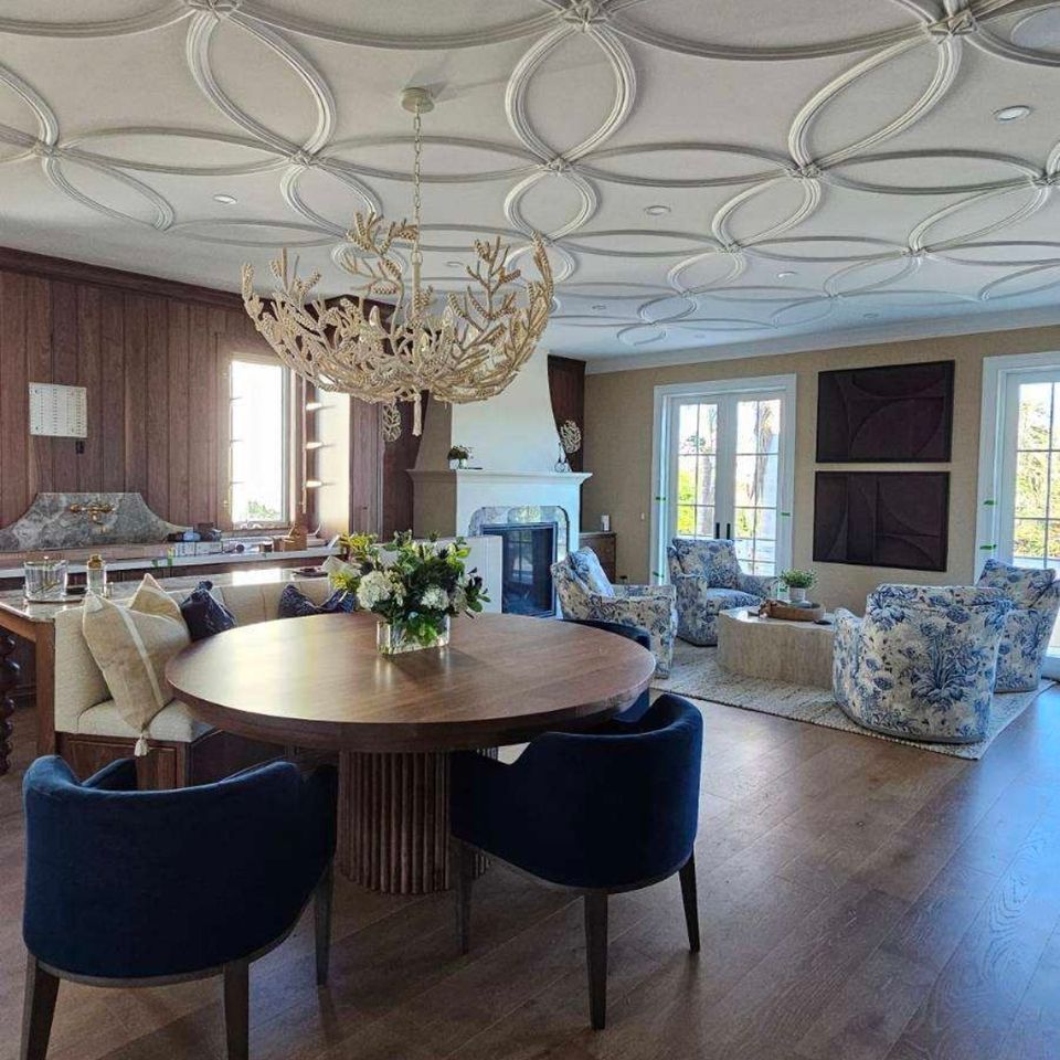 Open living and dining area with detailed ceiling trim and wide plank wood flooring