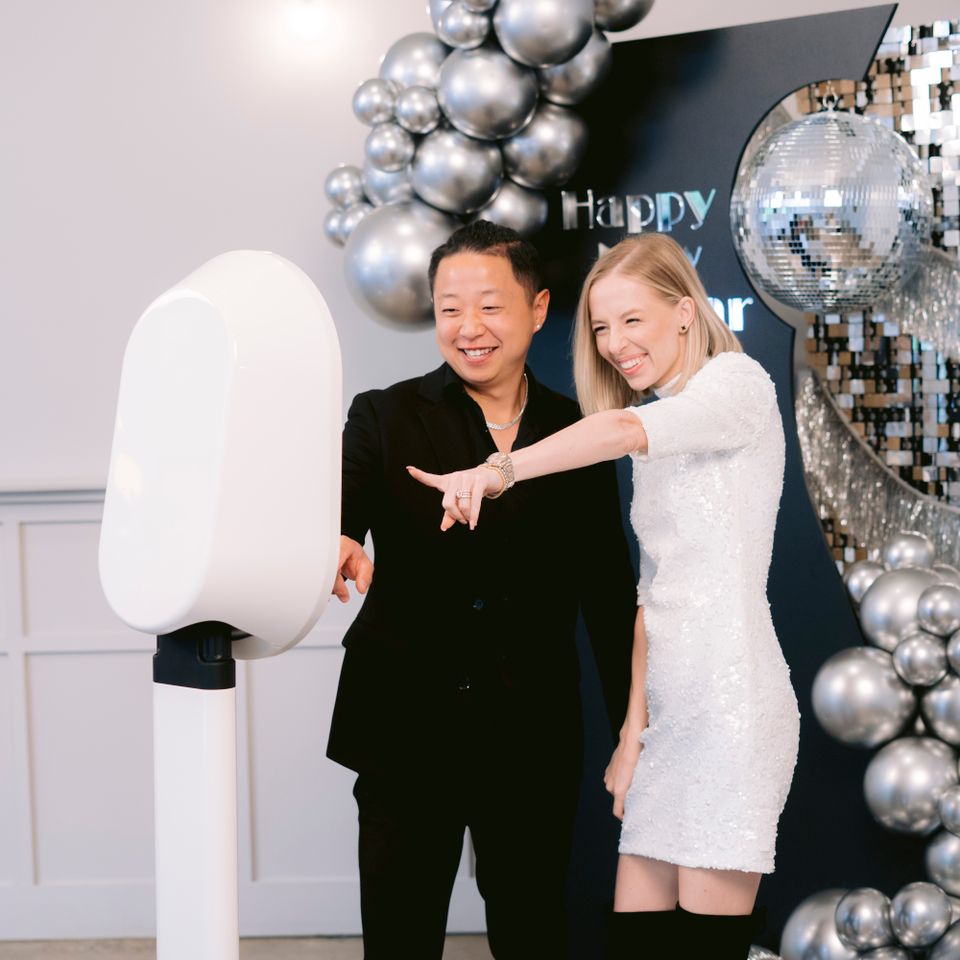 Two guests interacting with a sleek photo booth during a celebration.