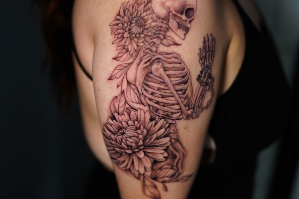 Image of a skeleton surrounded by flowers top and bottom