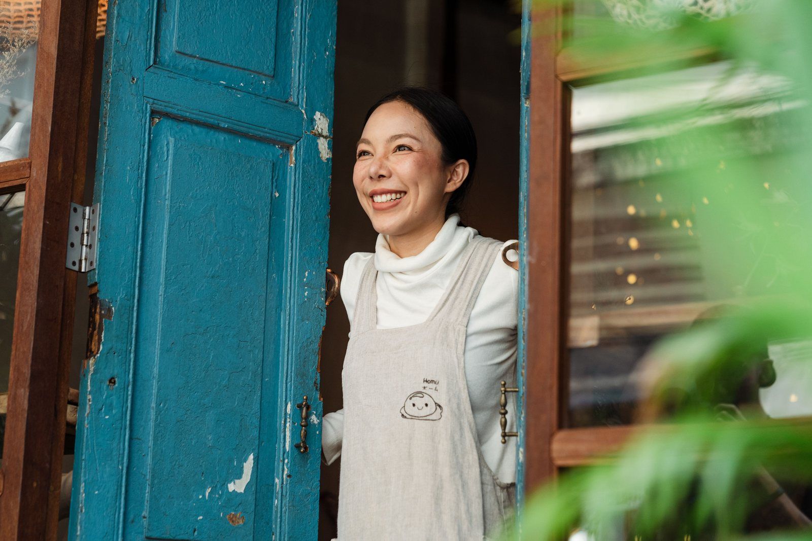 Smiling small business owner standing at the door of her local cafe