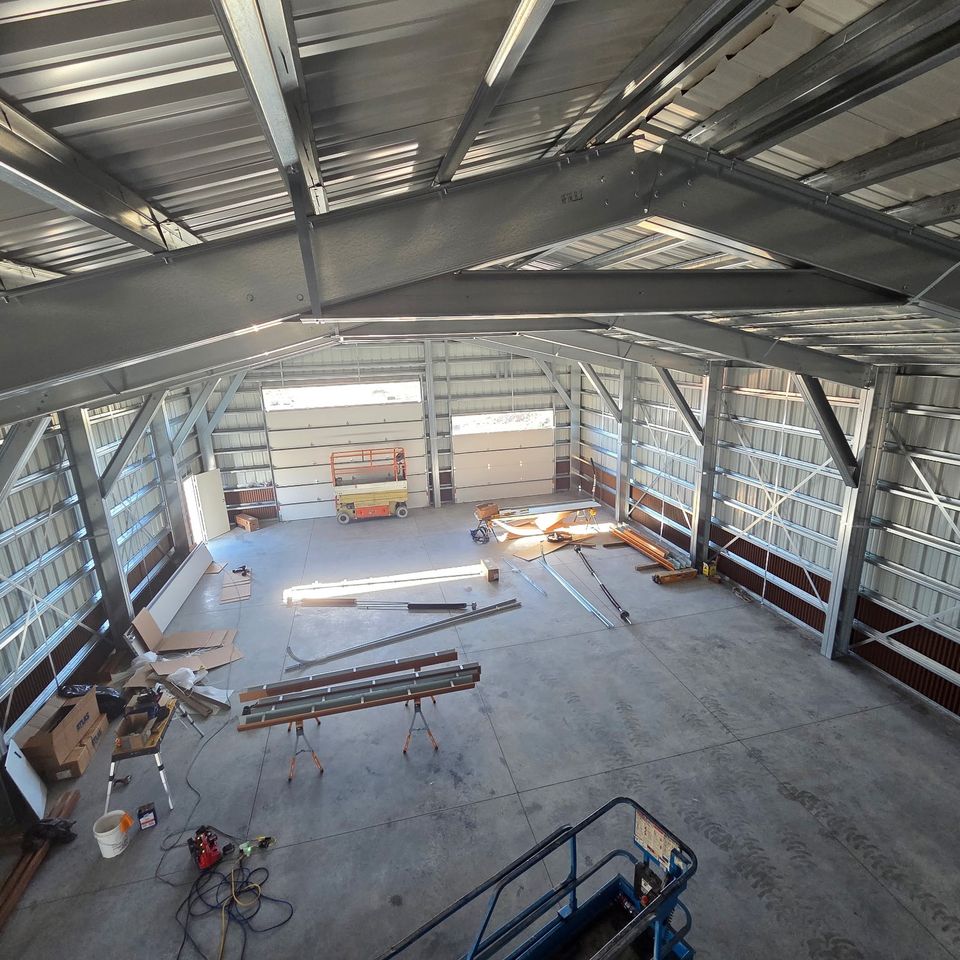 Interior view of open steel framing and concrete floor inside a metal building under construction