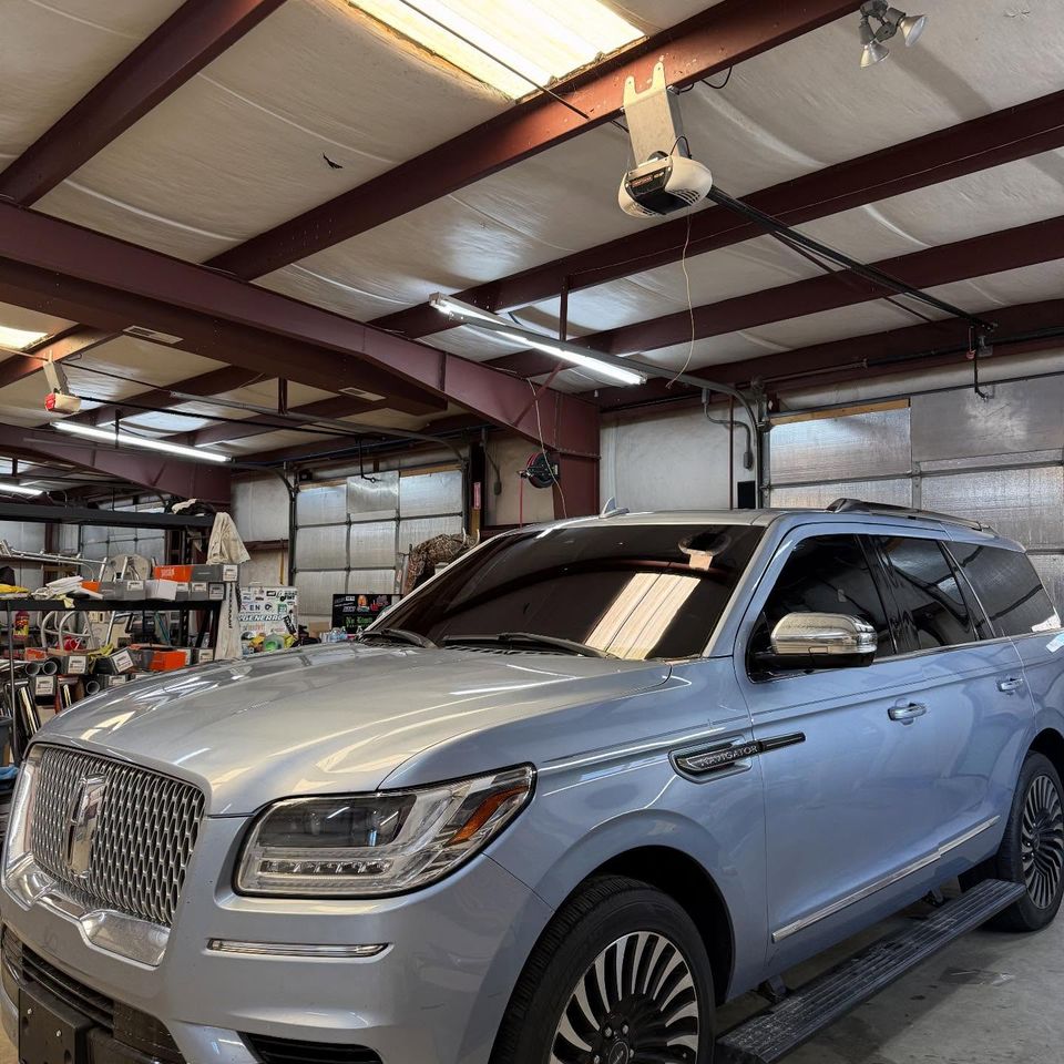Silver Lincoln Navigator with freshly tinted windows inside the auto tint shop bay