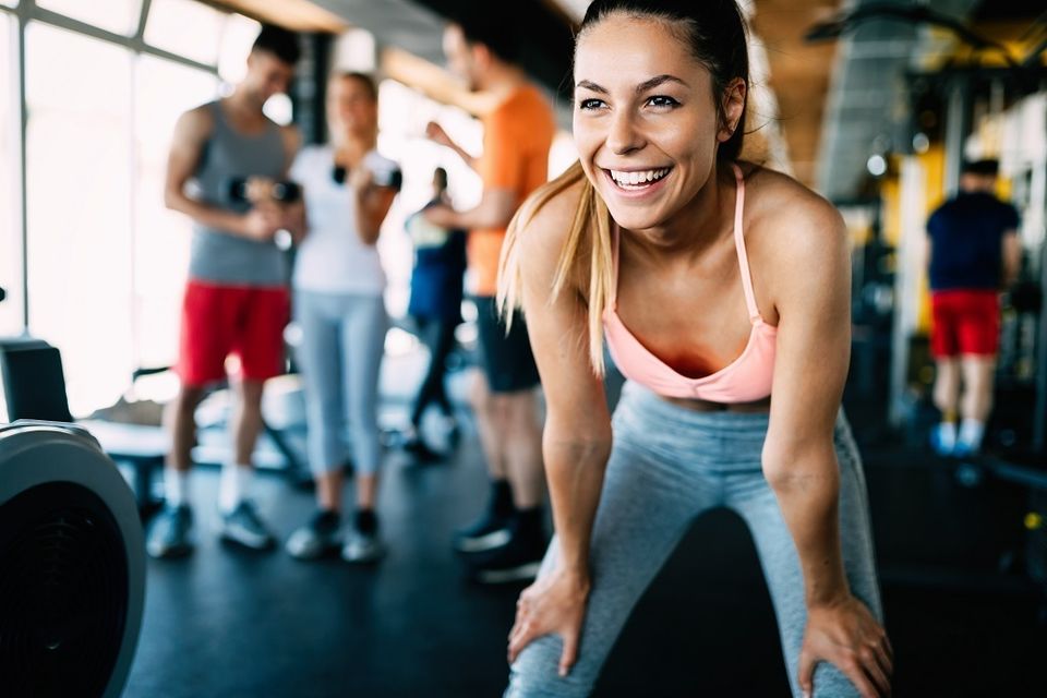 Woman smiling in the gym after working out with full range of motion