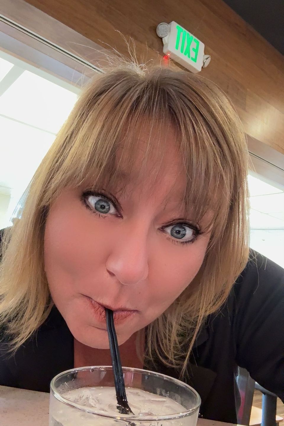 Tracy smiling while sipping a drink through a straw at a restaurant.