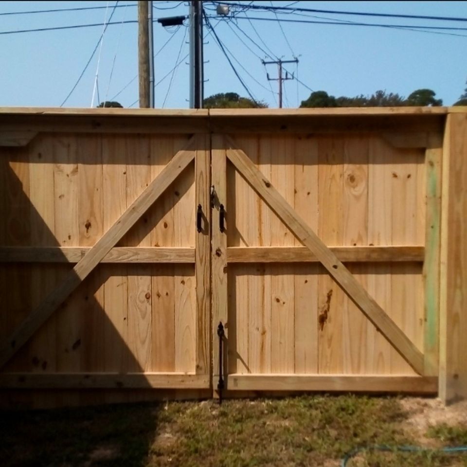 Double wood gate with cross-brace design and black hardware between brick buildings in Virginia Beach VA