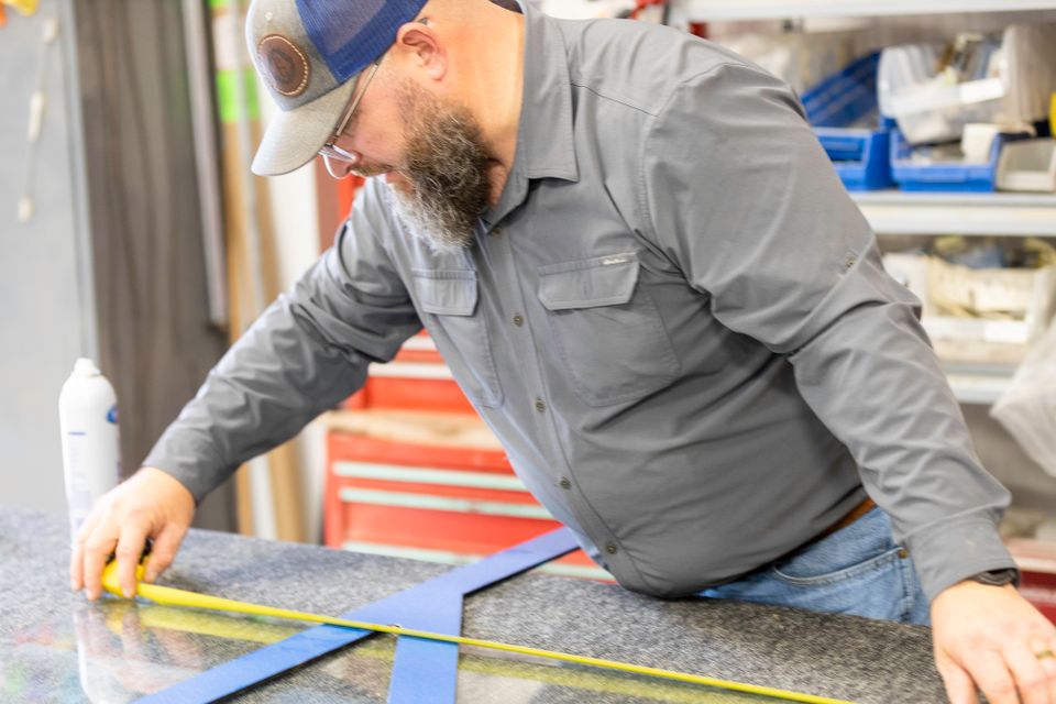 Close view of a glass professional measuring a panel with a tape measure and framing square