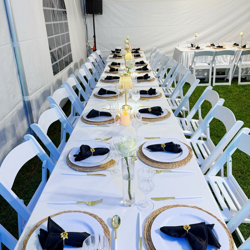 Tented banquet table with black napkins, woven chargers, and gold flatware styled in the Hamptons NY