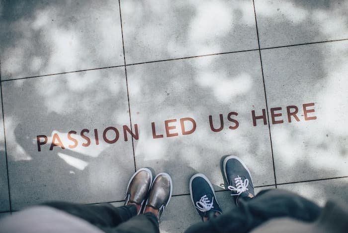 Two people's feet with the words "Passion Led Us Here" on the sidewalk 