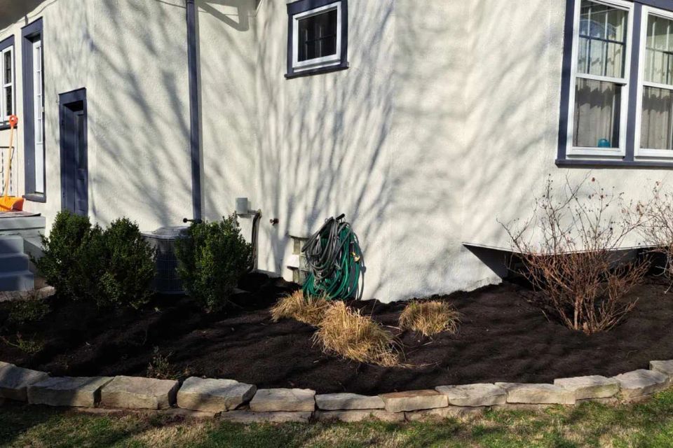 Side landscape bed with fresh black mulch surrounding shrubs and foundation plantings.