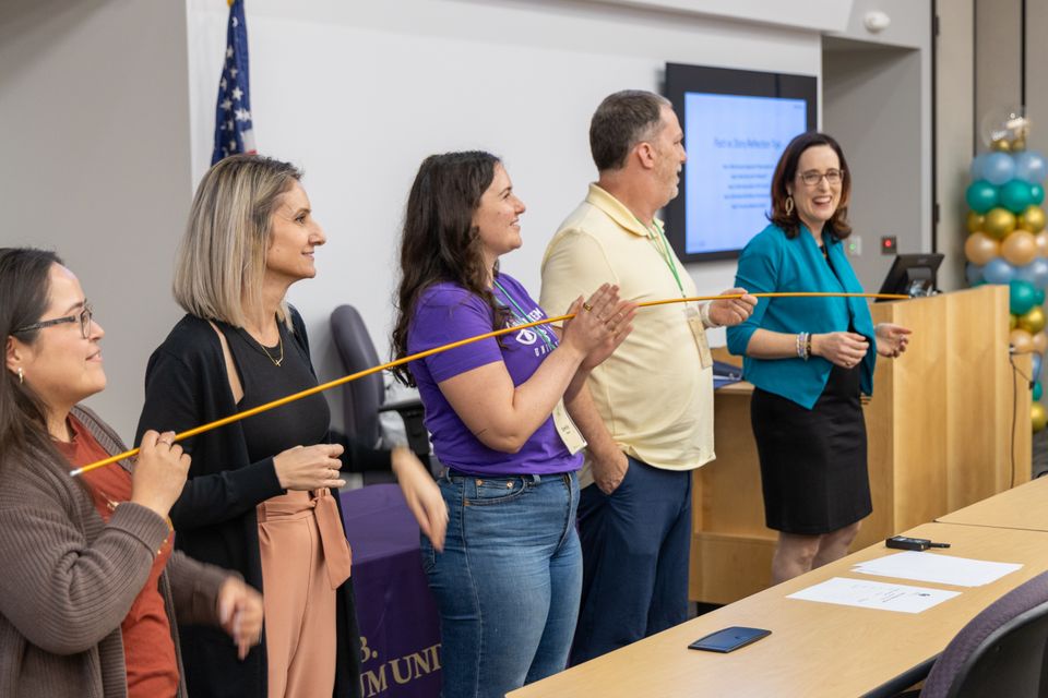 Five people standing holding a stick