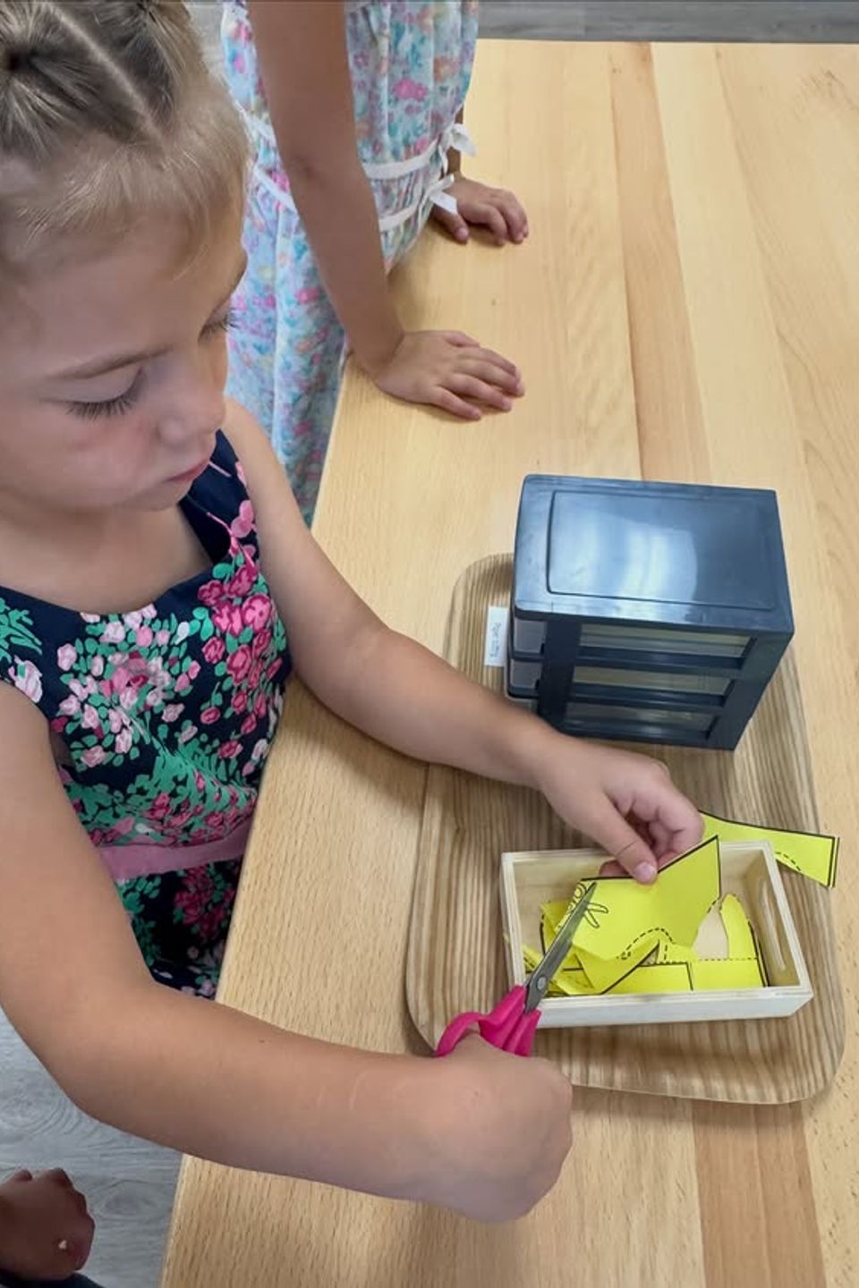 Preschool girl cutting paper shapes with scissors during a Montessori fine motor activity in Palmdale CA