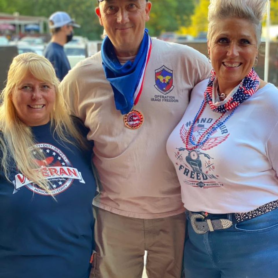 Two veterans and Kelly smiling together at a veteran appreciation gathering.
