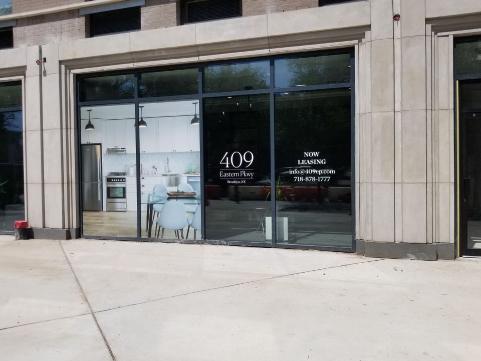 White cut-vinyl address logo and leasing details applied to a large storefront window