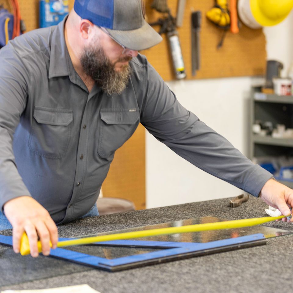 Phillip’s Glass professional measuring a glass panel with a tape measure and square