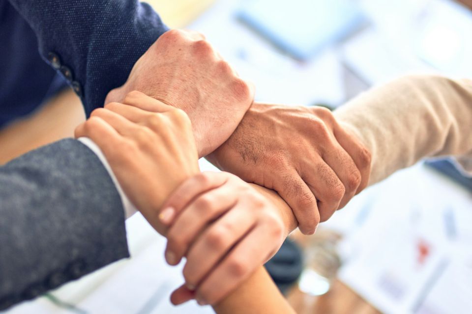Group of hands joined together showing teamwork and support in senior home care in Long Island NY