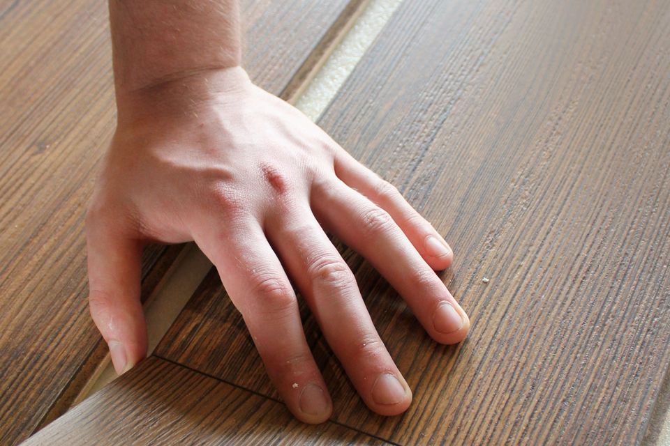 Hand pressing down a laminate flooring plank during a floor installation