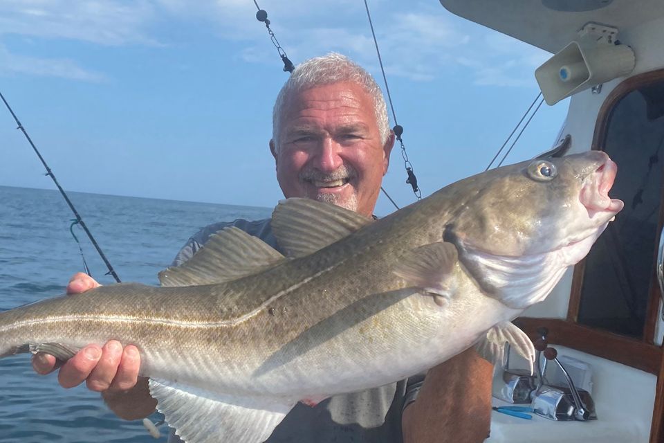 Capt stan holding striper on boat zoomed in