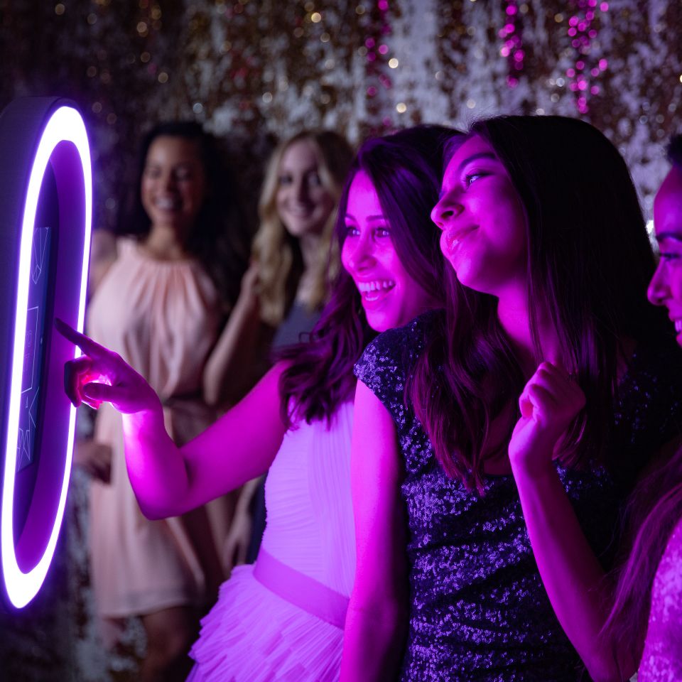 Group of guests using a digital photo booth at a party with colorful lighting