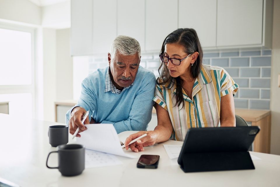 A couple sitting together at a cozy table with a financial advisor, reviewing their life and financial insurance options with confidence and peace of mind. Secure your future with Stewart & Associates Insurance.