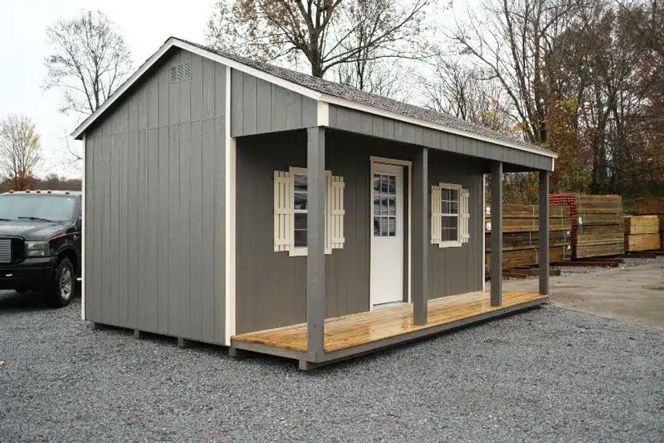 Gray country cabin with covered porch, shutters and white entry door in Knoxville TN