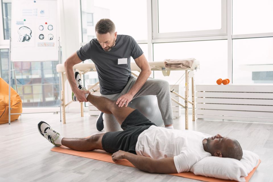 Physical therapist treating a patient's leg injury during a sports rehabilitation session