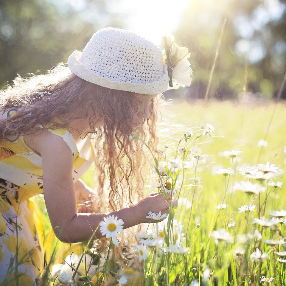 Woman smelling flowers outdoors, representing natural wellness and healthy lifestyle