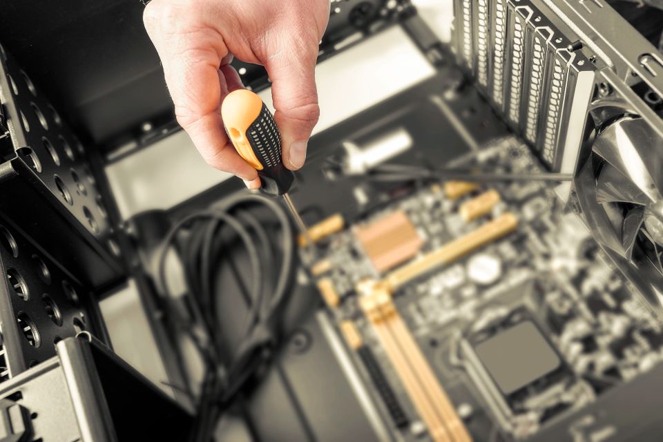 A man using a screwdriver, working on repairing the inside of a computer, used in a blog by Cannone Marketing.