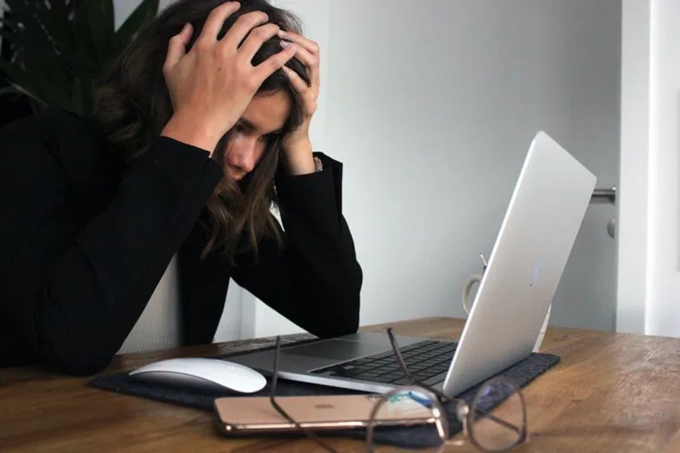 Woman looking at her laptop screen seeming very stressed out or frustrated