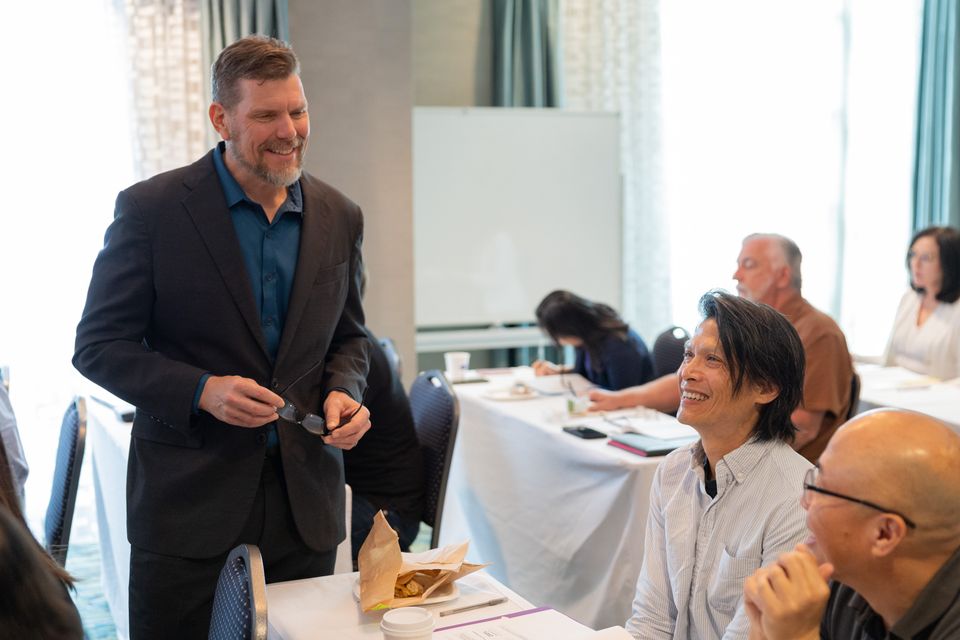 Man standing talking to two seated people