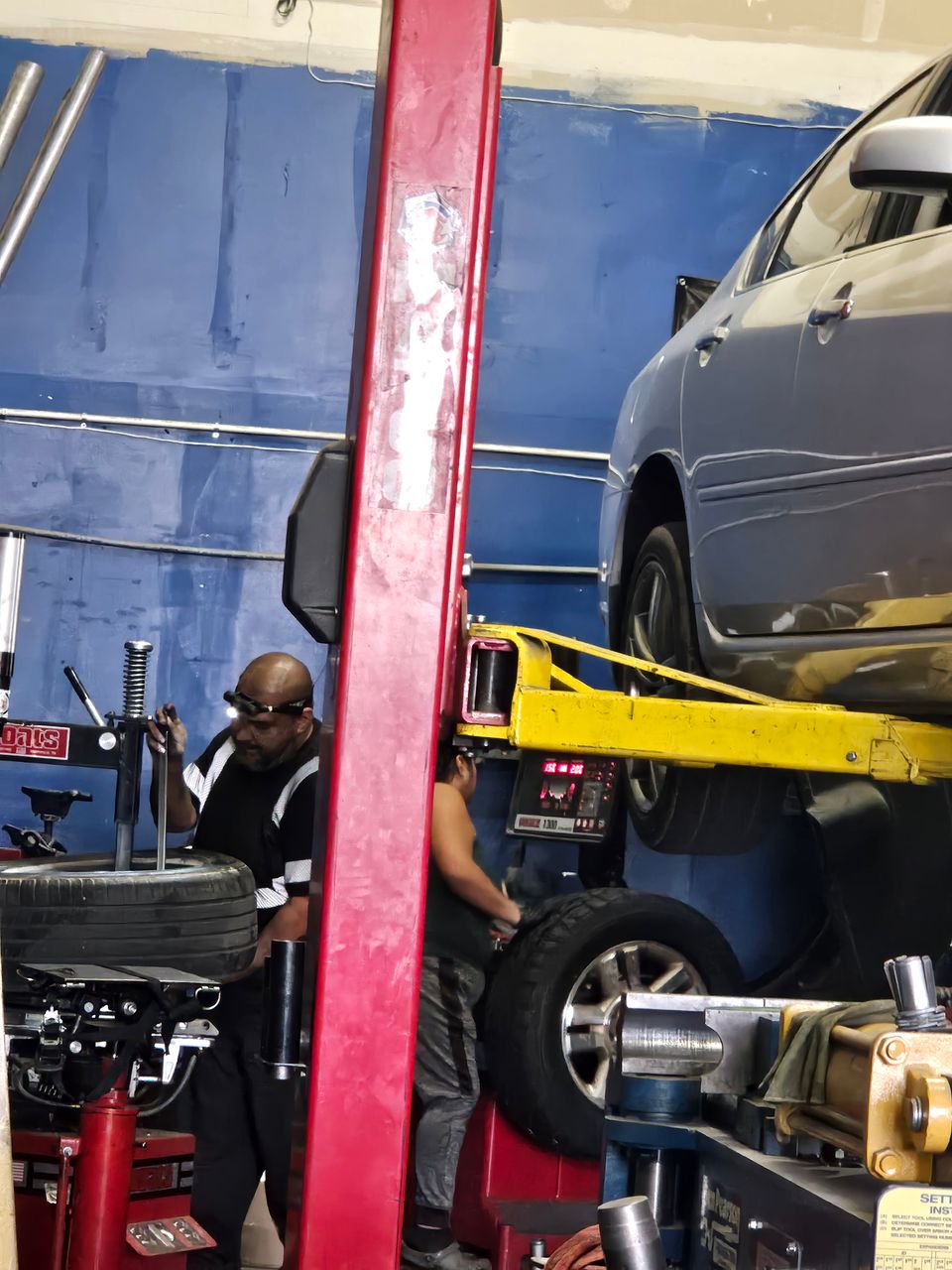 Image of a car on the lift and tires being attended to.