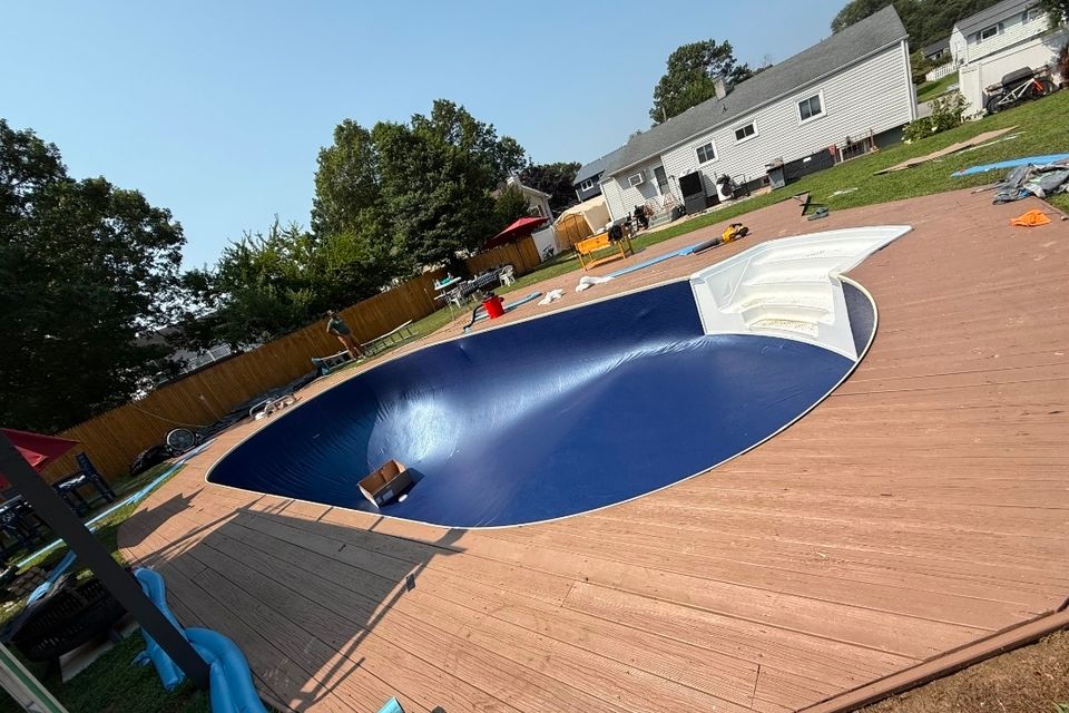 Oval above ground pool with a new dark blue liner set before filling on a wood deck