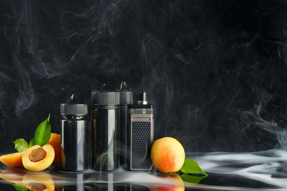 Vape and smoking liquid with fruit against black