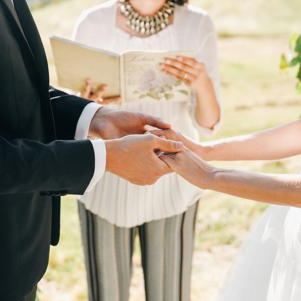Couple holding hands while officiant reads vows during wedding ceremony