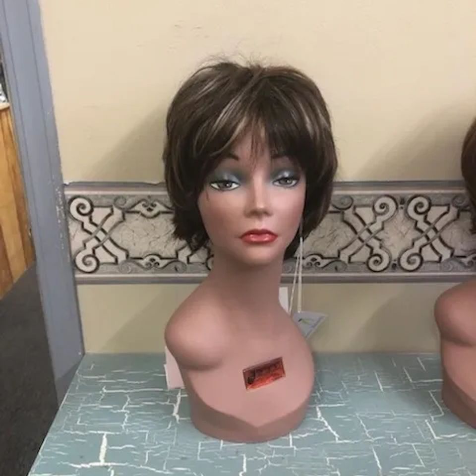 Short brunette wig with layered styling and soft volume displayed on a mannequin at Shears Wigs & Hairpieces Salon.