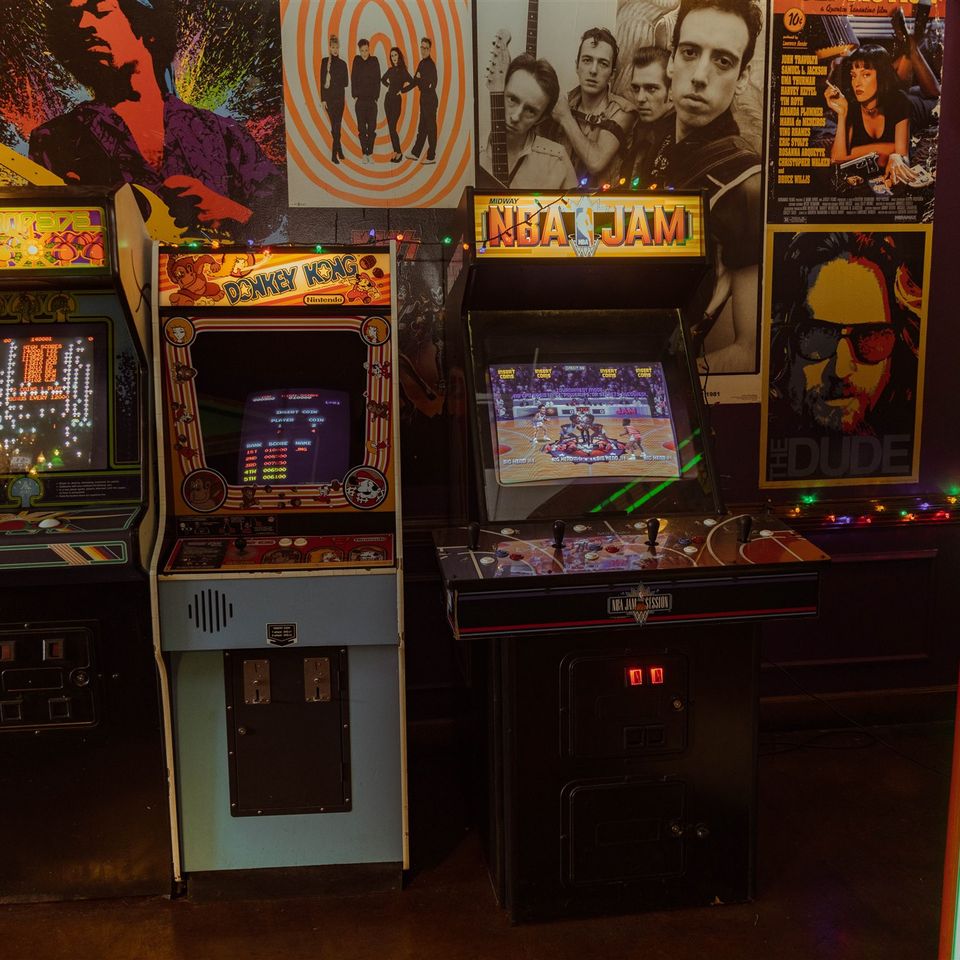 Boxing arcade machine with other games around it and large album art on the walls around it