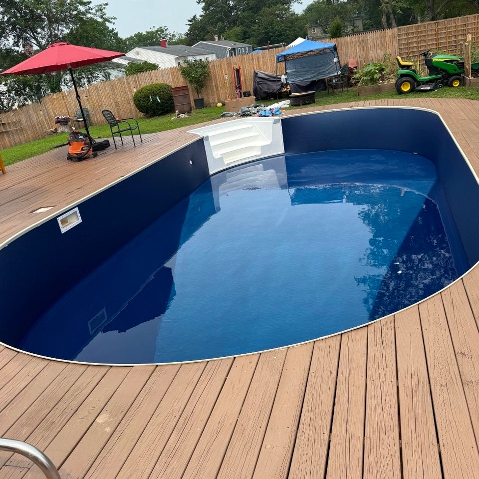 Above ground pool with navy liner and white step unit installed on a backyard deck