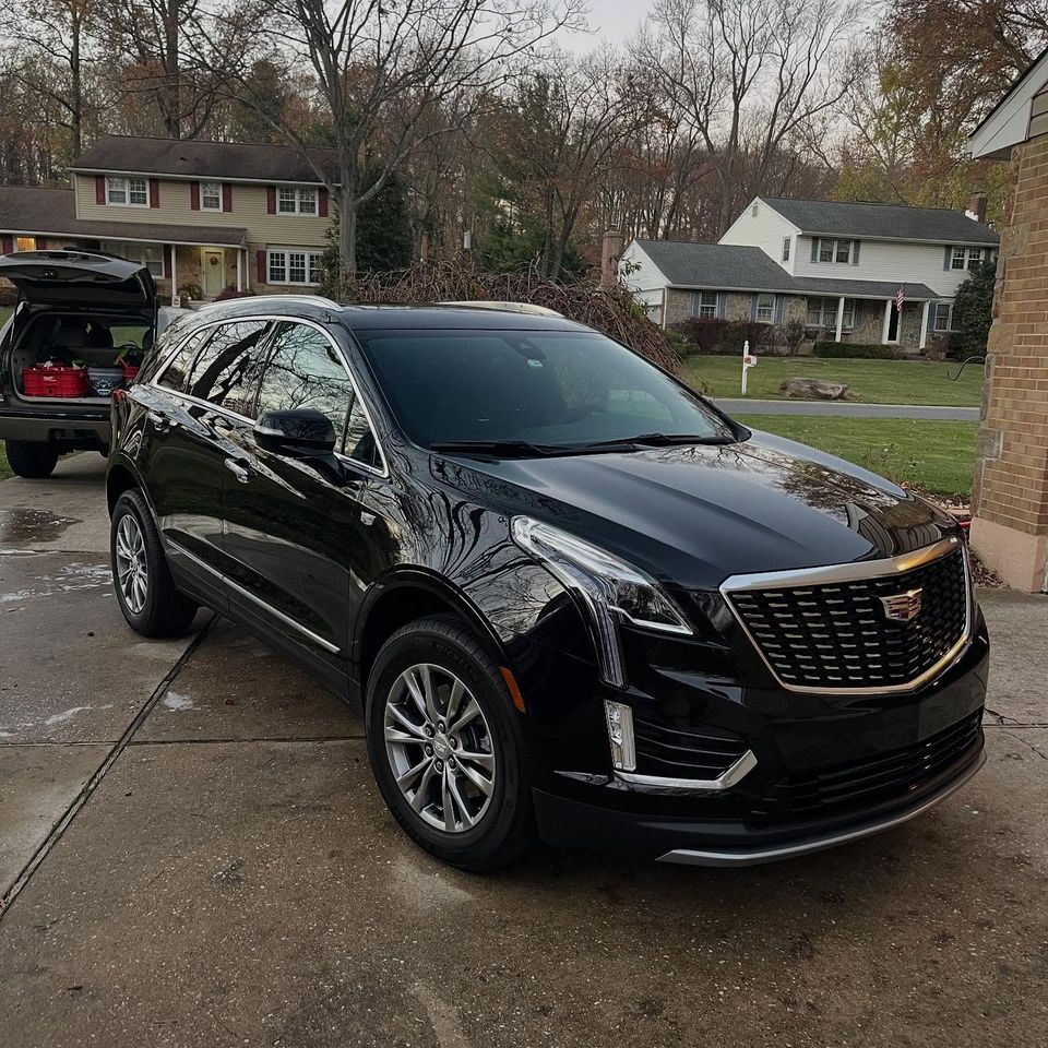 Glossy black Cadillac XT5 parked in a residential driveway after a mobile exterior detail near Wilmington