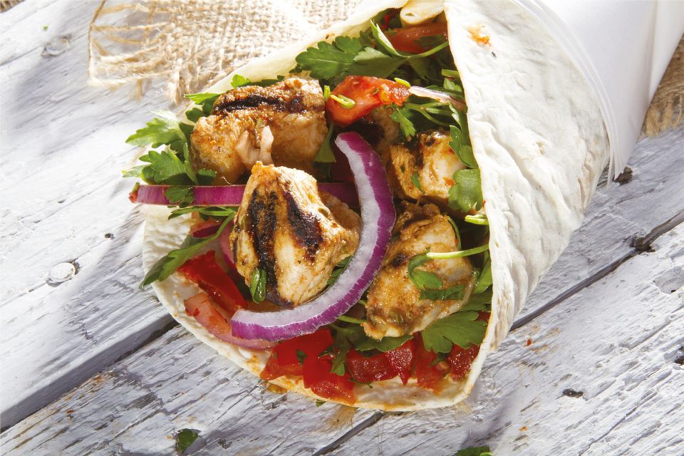 Grilled chicken wrap with lettuce, tomatoes, red onions, and fresh herbs.