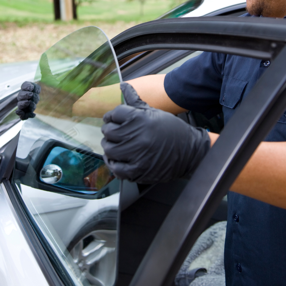 Technician installing a replacement side window on a vehicle using professional auto glass techniques.