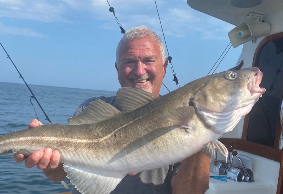 Capt stan holding striper on boat zoomed in