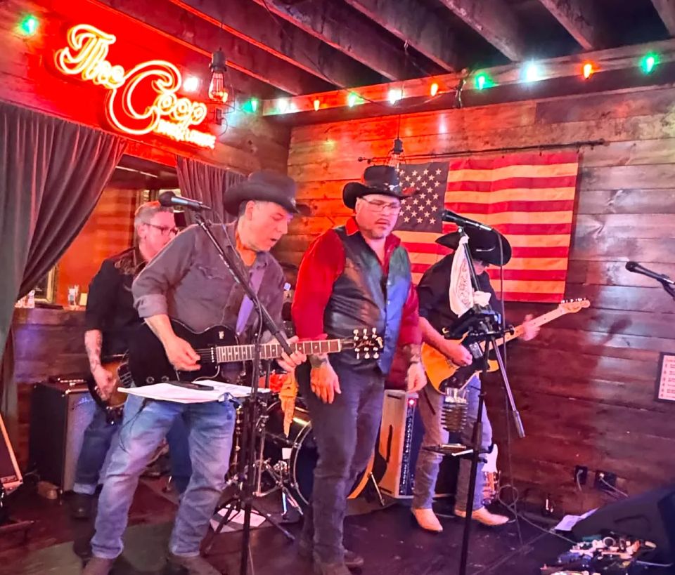 Roadside band members in cowboy hats performing guitars and vocals on stage at a Long Island NY bar