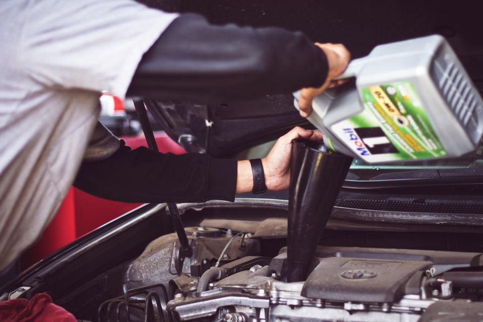 Image of mechanic adding oil to an engine as a routine part of Johnny's Radiator and Auto Repair Maintenance program.