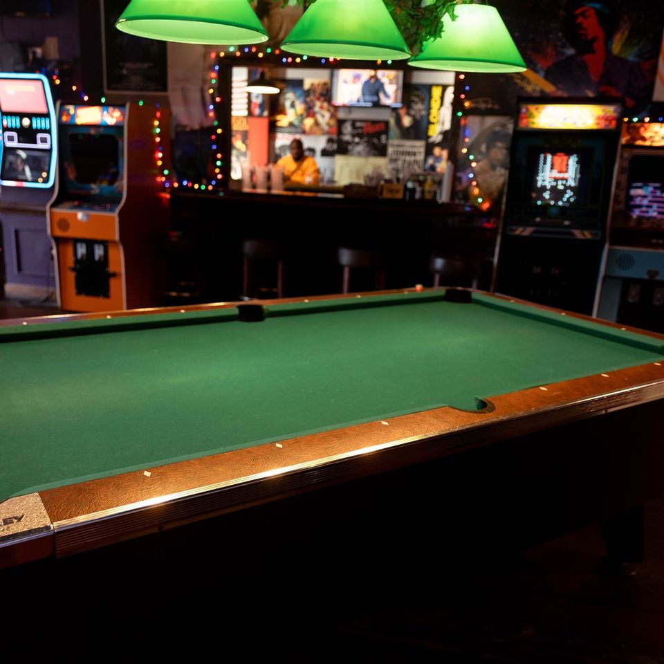 Pool table with arcade games and jukebox in the background