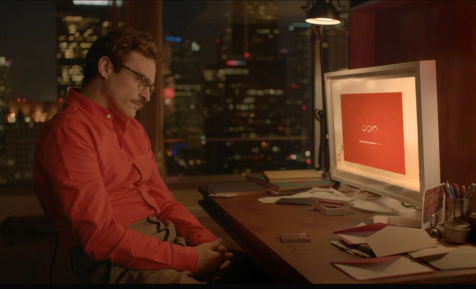 Joaquin Phoenix from the movie "Her" sitting at a desk slumped over looking at a computer screen 