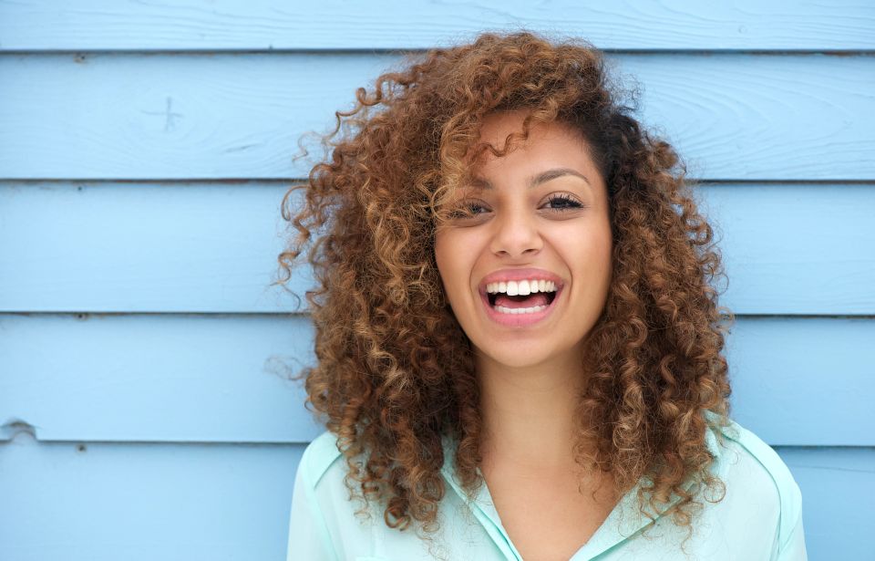 Close-up of a woman smiling, representing the feeling of comfort and relief from PMS symptoms